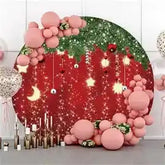 Red and green christmas tree backdrop with glittery ornaments and pink balloons.